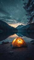 Camping tent on the shore of a lake at night photo