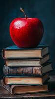 An apple sits on top of a stack of books photo