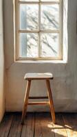 A wooden stool sitting in front of a window photo