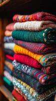 A stack of colorful knitted sweaters on a shelf photo