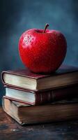 An apple sits on top of a stack of books photo