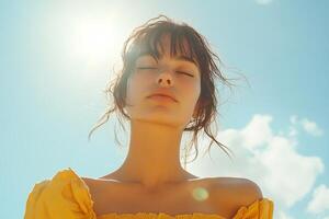 A woman in a yellow dress is looking up at the sun photo