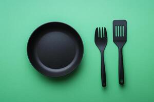 A black frying pan and fork on a green background photo