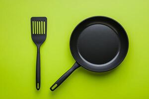 A frying pan and spatula on a green background photo