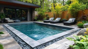 A backyard pool with a stone patio and lounge chairs photo