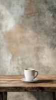 A cup of coffee on a wooden table in front of a wall photo