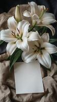 White lilies and a blank card on a bed photo