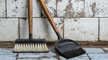 Two old broom and dustpan on a tiled floor photo