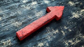 A red arrow pointing upward on a wooden surface photo
