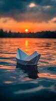Paper boat floating in the water at sunset photo