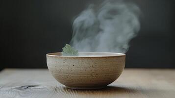 A bowl of steaming tea with a leaf in it photo