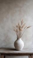 Beautiful dried flowers in ceramic vase on rustic wooden table against textured wall photo