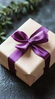 A brown gift box with purple ribbon on a dark surface photo