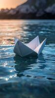 Paper boat floating in the ocean at sunset photo