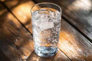 A glass of water sitting on a wooden table photo