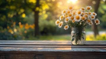 A mason jar with daisies on a wooden table in the sun photo