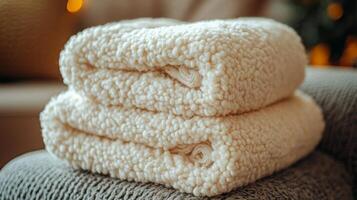 A stack of two white blankets on a couch photo