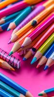 Colorful pencils arranged in a vibrant display on a bright pink background photo