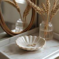 Decorative plate with rings and dried flowers on a marble surface reflecting golden mirror photo