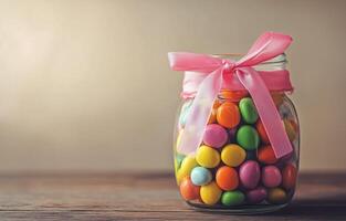 Colorful candy jar with ribbon on wooden table surrounded by soft light photo