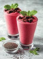 Refreshing berry smoothie topped with chocolate and mint sprigs served in clear glasses photo