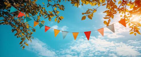 Colorful flags hanging between branches on a sunny day with blue sky and clouds photo