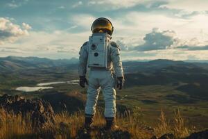 Astronaut standing on top of a mountain looking at the valley photo