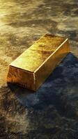 Gleaming gold bar rests on a textured dark surface photo
