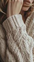 A woman in a sweater is holding her hand to her face photo