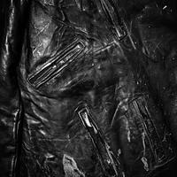 Close up shot reveals a worn black leather jacket detail photo