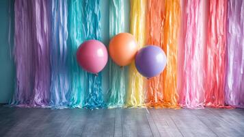 Three balloons and a rainbow streamer in front of a wall photo