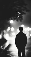 A man is walking down the street at night photo