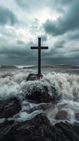 A cross is standing on a rock in the middle of the ocean photo
