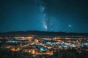 The milky shines brightly over a city at night photo