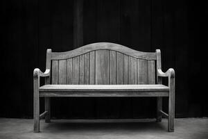 A black and white photo of a bench sitting in front of a wall