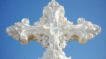 Ornate white cross against a clear blue sky highlighting intricate design details photo