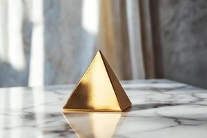 Golden pyramid sculpture on a marble surface reflecting modern design and elegance photo
