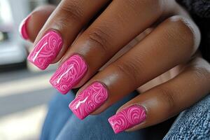 Vibrant pink nail art with intricate swirls displayed on a hand in a casual setting photo