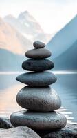 Balanced rock stack stands peacefully against a mountain backdrop photo