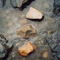 Rocks varying in color and size sit in flowing water photo