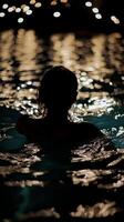 A woman in the water at night with lights in the background photo