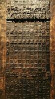 Carved stone panel displaying people and grid of symbols photo