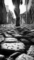 Bare feet walking down old cobblestone street in black and white photo