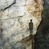 Silhouette of person stands before weathered rock face markings photo