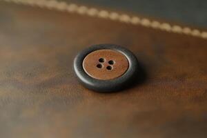 A brown and black button resting on textured brown leather photo