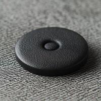 Black textured circular object with central raised button shape photo