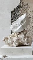 White porous rocks stacked on a plinth against a textured wall photo