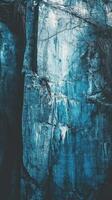 A textured stone cliff face in cold hues is shown photo