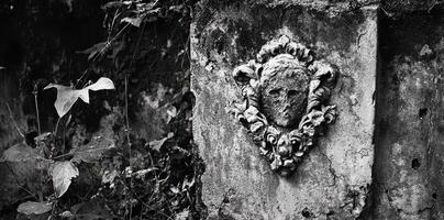 Old weathered stone wall with a sculpted face decoration photo