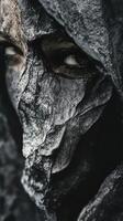 A dark figure with a textured mask and visible eyes photo